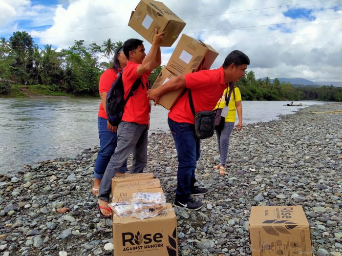 ICM staff carrying food packs to a remote community in Kalibo